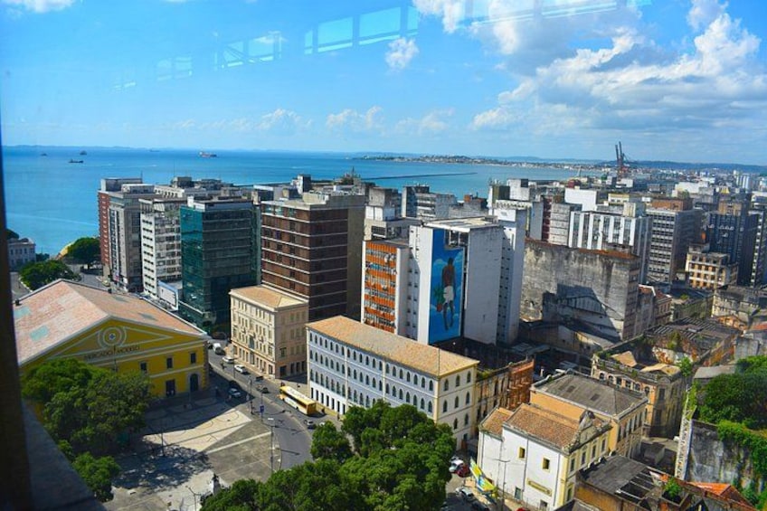 A cityscape with a mix of modern and historic buildings, a clear blue sky, and a body of water in the distance. 2
