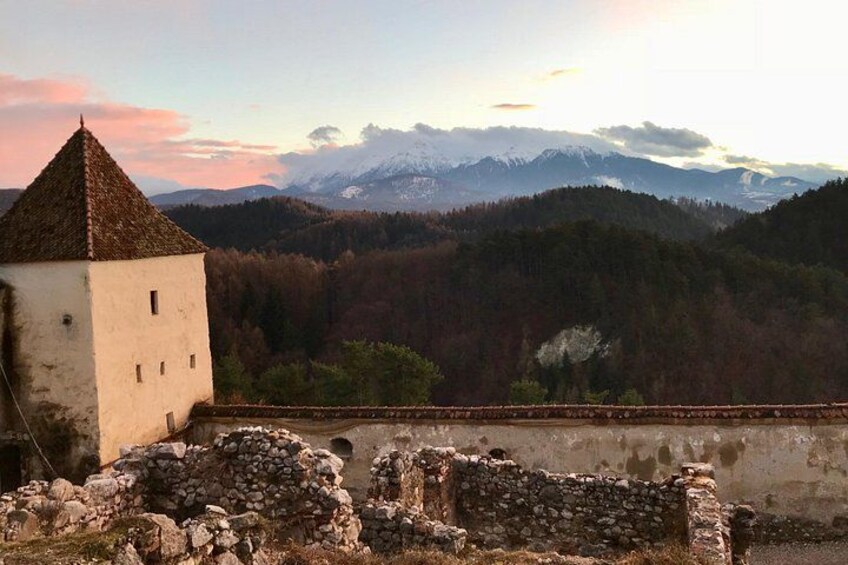 A tower, a stone wall, and a mountainous landscape. 4