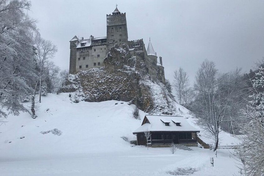 A castle on a snow-covered hill with a wooden building in the foreground. 2
