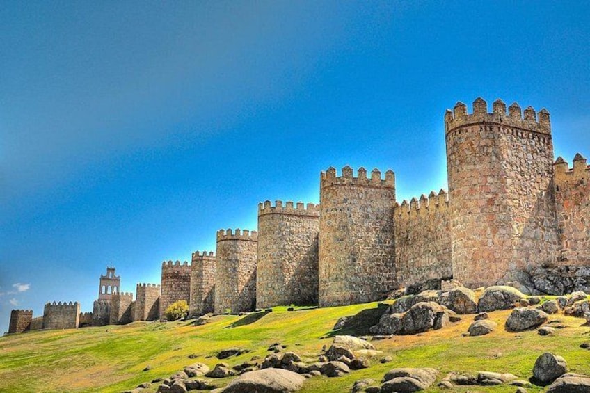 A stone castle with multiple towers and a grassy hill. 1