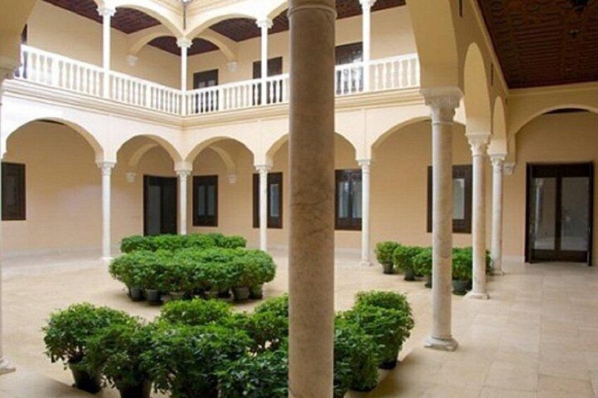Un cortile con colonne, un balcone e piante in vaso. 4