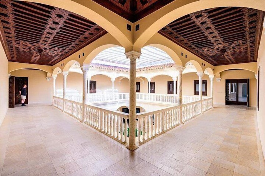 Un ampio cortile con archi, pavimento piastrellato e soffitto in legno. 5