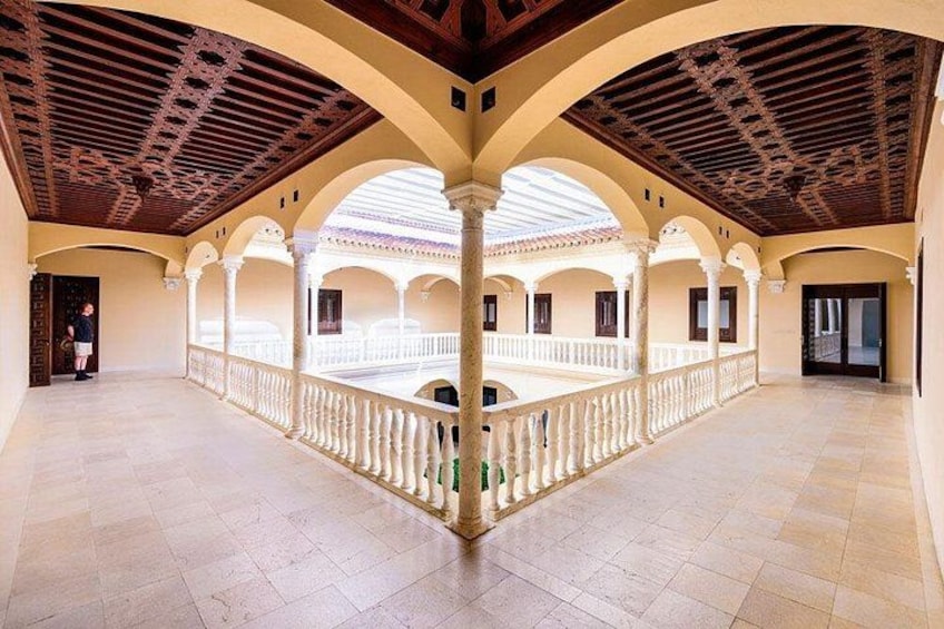 Un amplio patio con arcos, suelo de baldosas y techo de madera. 1