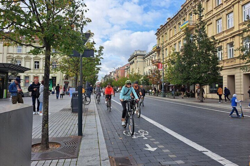 Una calle urbana con ciclistas, peatones y edificios. 1