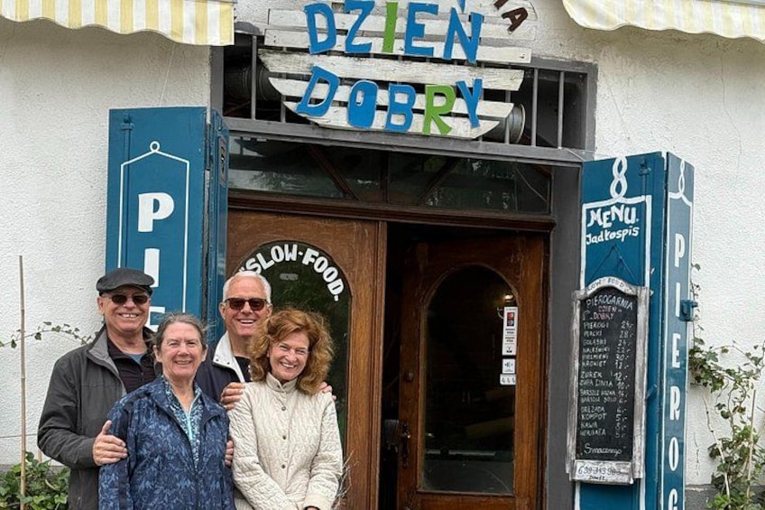 A restaurant named DZIEN DOBRY with a signboard, a menu board, and a parking sign. 2