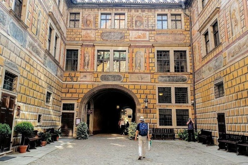 Un cortile con un'ampia entrata ad arco, pareti piastrellate e piante in vaso. 2