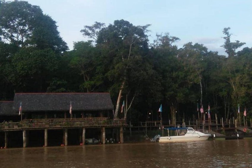 A dock with a building, a boat, and a forested area. 2