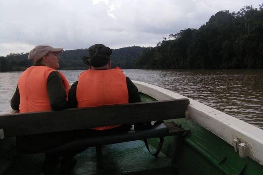 Two people in orange life jackets on a green boat. 3