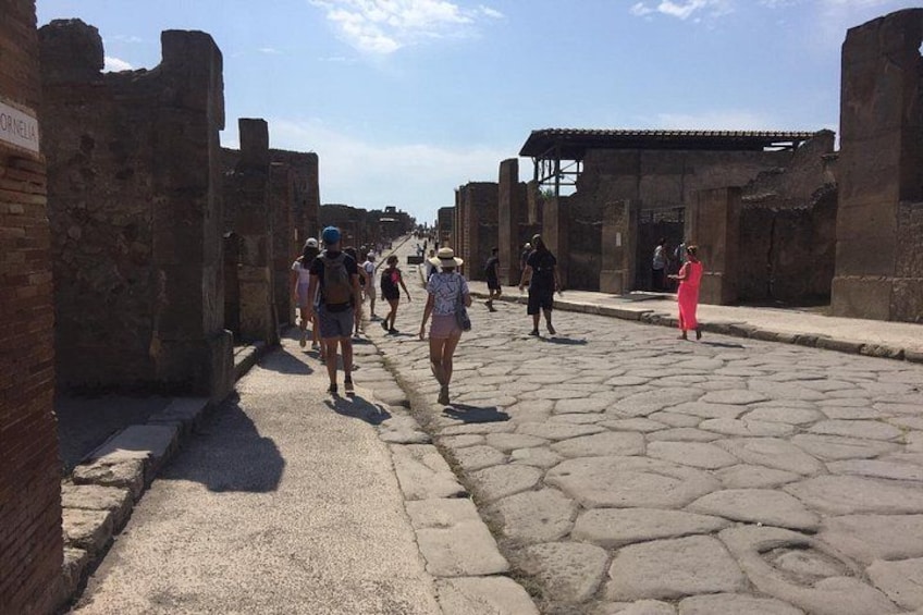 An ancient stone pathway with visitors walking through ruins. 2