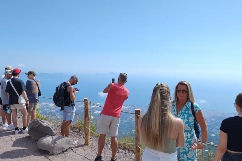 Een groep mensen staat op een rotsachtige uitkijkpost, met uitzicht op een verafgelegen landschap. 1