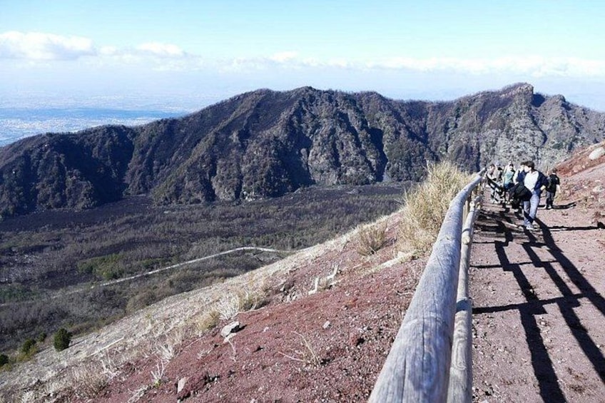 A group of hikers on a mountain trail with rocky terrain and a view of distant mountains. 2