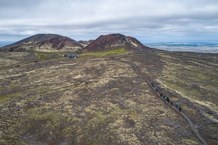 Eine bergige Landschaft mit einem gewundenen Pfad und einer Gruppe von Wanderern. 2