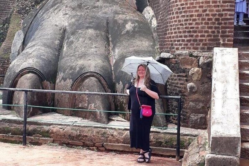 A person standing in front of a large stone structure with a railing. 1