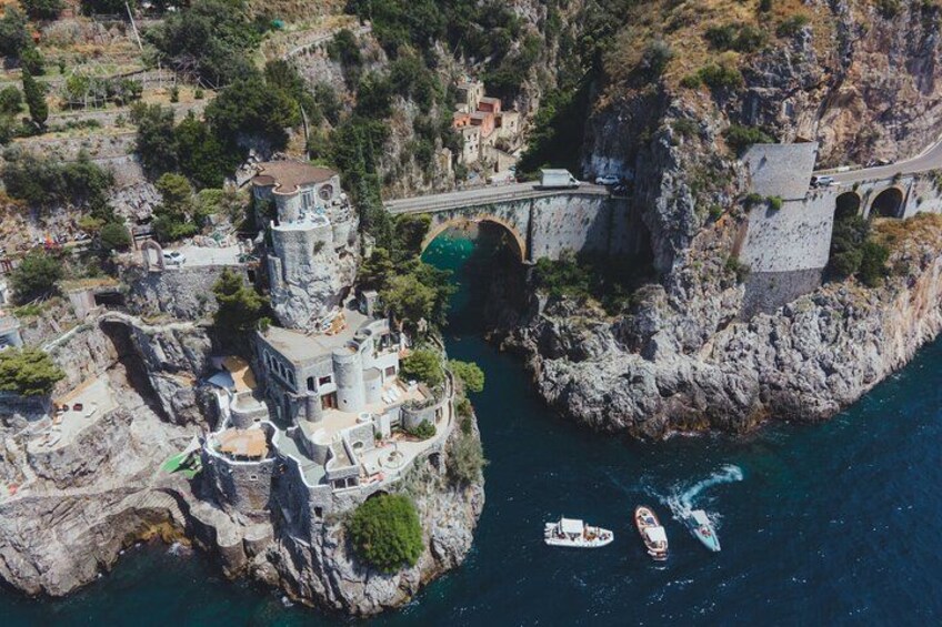 A coastal town with a castle-like structure, a bridge, and boats on the water. 4