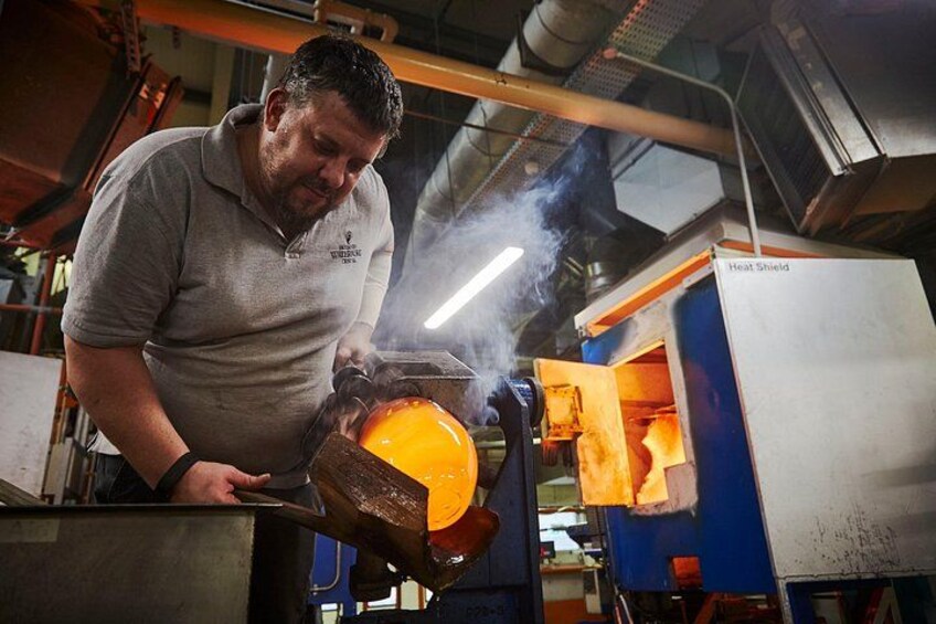 Una persona trabajando con un objeto naranja grande en un taller con un escudo térmico y maquinaria. 2