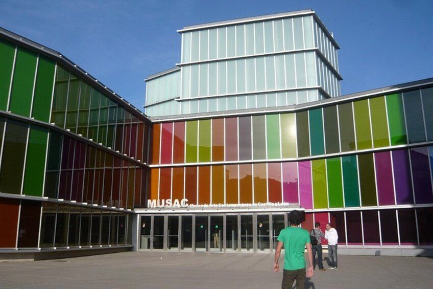 Een modern gebouw met grote glasramen en een bord waarop 'MUSAC' staat. 3