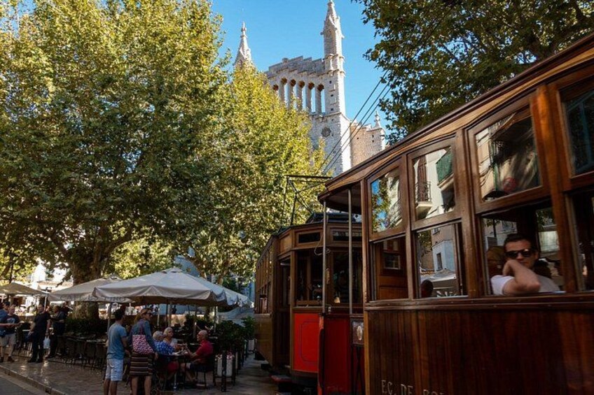 Un tranvía de madera, cafés al aire libre y un edificio histórico con torres. 5