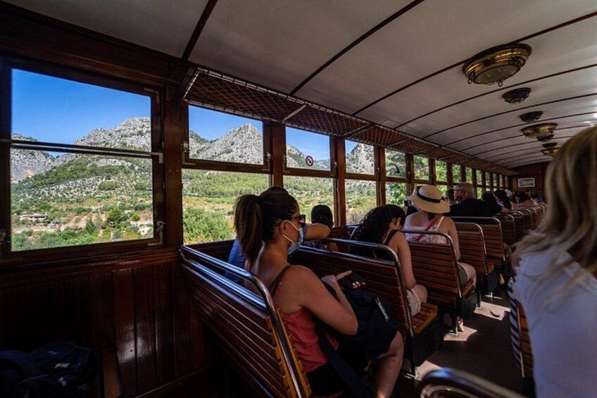 Interior de un tren con pasajeros sentados, grandes ventanales que muestran un paisaje montañoso. 3