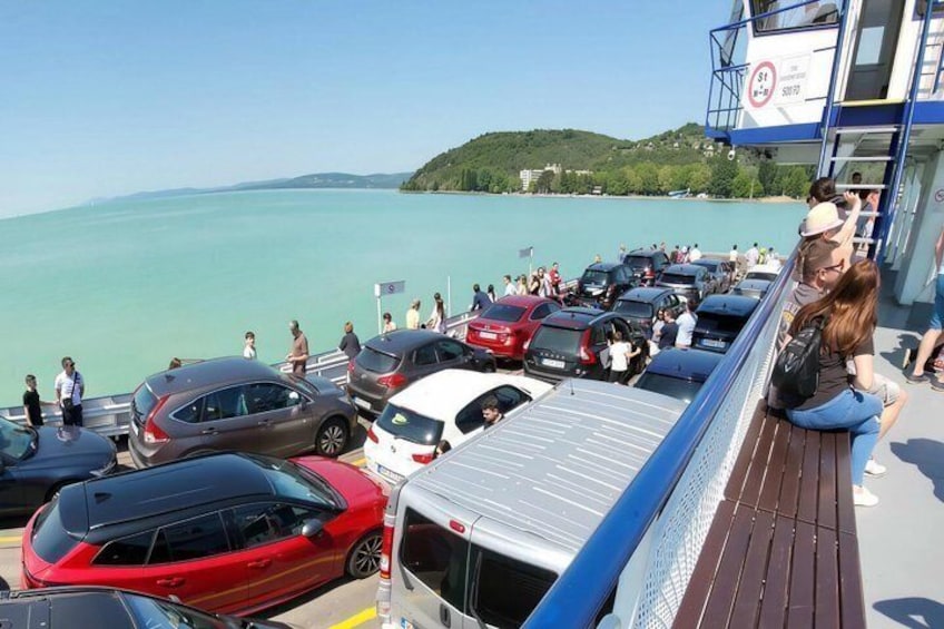 A ferry dock with parked cars and people. 3
