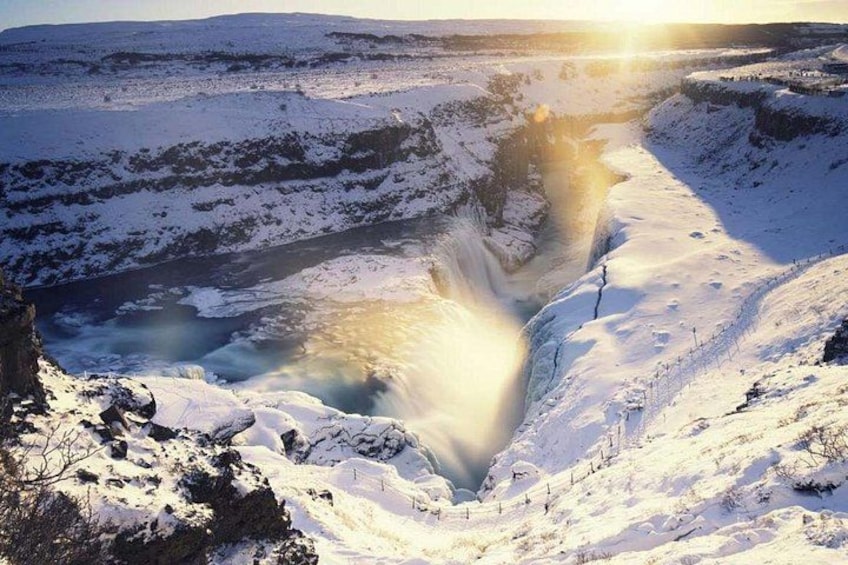 Paisaje nevado con cascada, río y un sol distante. 3