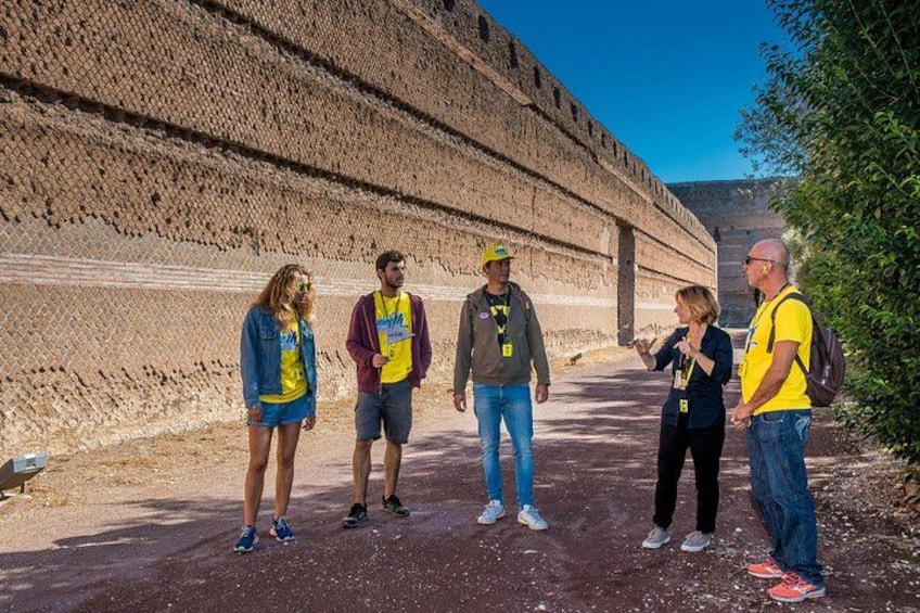A group of people standing on a dirt path near a large, ancient stone structure. 5