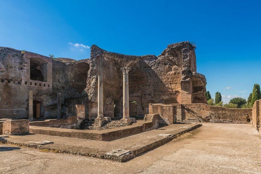 Ancient ruins with columns and a large stone structure. 4