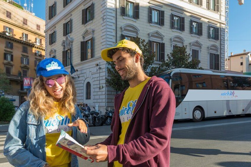 Dos personas de pie en una calle, con un autobús al fondo. 2