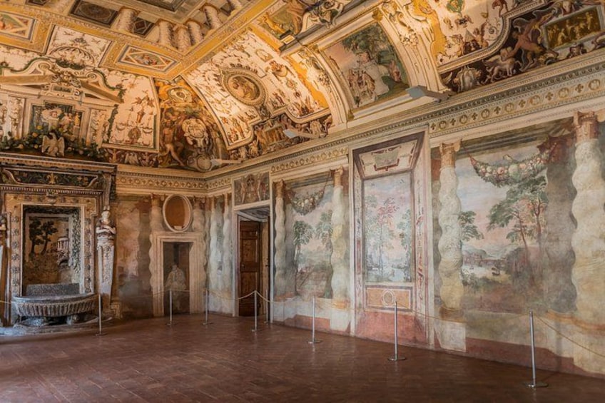 An ornate room with frescoes, columns, and a wooden floor. 2