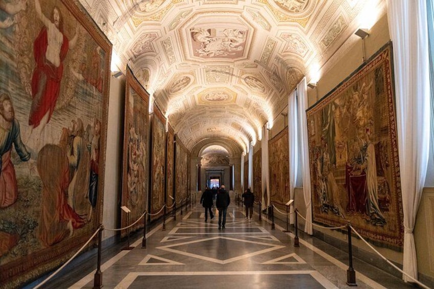 A grand hallway with high ceilings, ornate ceiling decorations, and large frescoes on the walls. 5