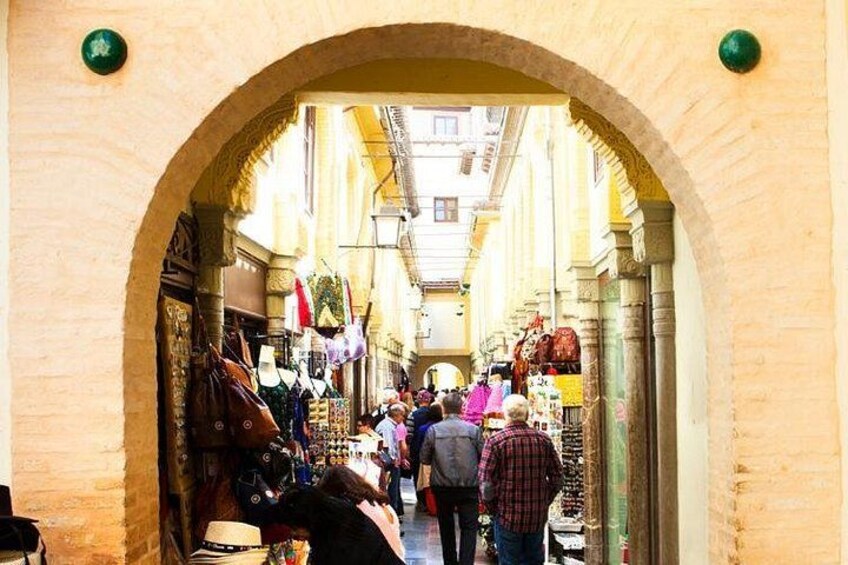 An archway leading to a market with people shopping. 5
