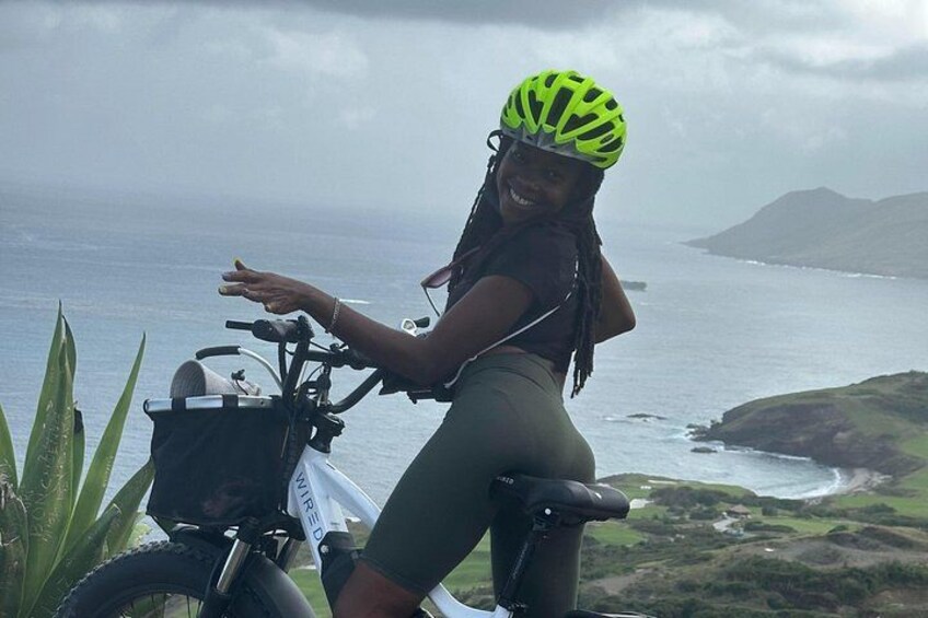 A person on a bicycle with a helmet, near a coastal landscape. 4