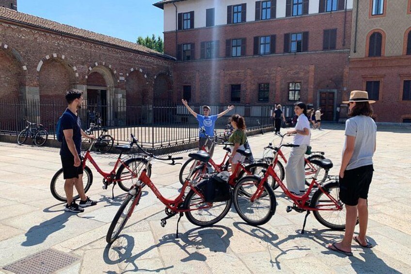 A courtyard with red bicycles, a brick building, and people standing around. 2