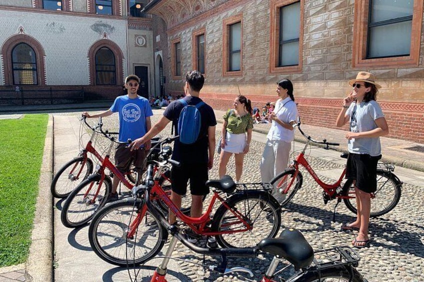 Un groupe de personnes se tient sur un chemin pavé de pierres, avec des vélos garés à proximité. 3