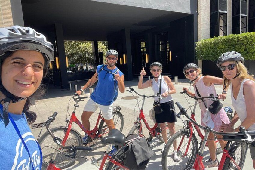 A group of people on bicycles in an outdoor setting with buildings in the background. 5
