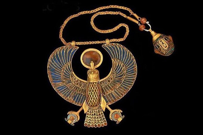 En guldfarvet vedhæng med et egyptisk falkedesign, et cirkulært vedhæng og en kvast. 4