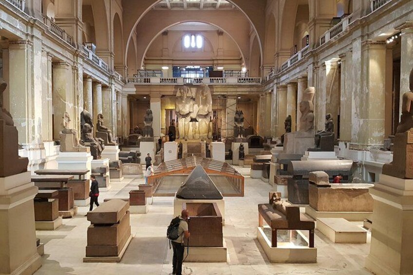 Et indendørs museum med ægyptiske oldtidsfund, herunder sarkofager og statuer, udstillet i en imponerende sal med højt til loftet og klassisk arkitektur. 3