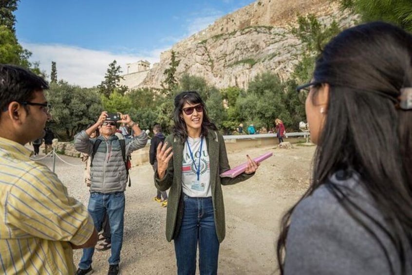 A group of people in a rocky outdoor setting, possibly a historical site, with one person holding a camera. 1