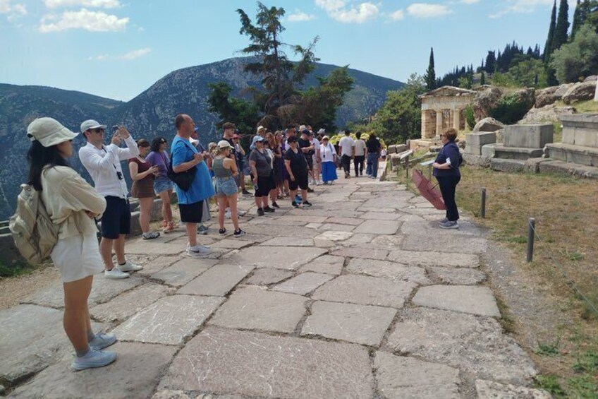 A group of people standing on a stone pathway at an archaeological site with ruins and mountains in the background. 5