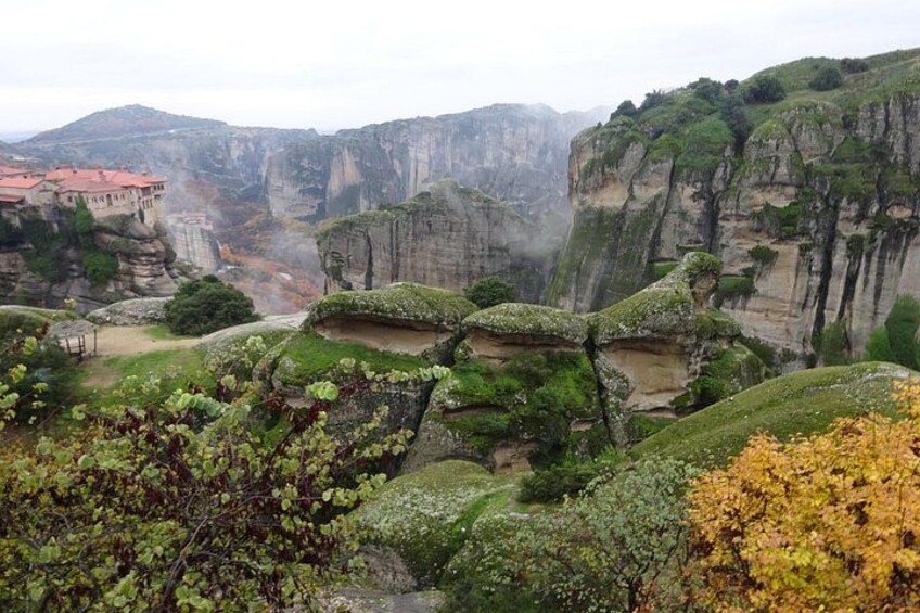 A mountainous landscape with rocky cliffs and a monastery with red-tiled roofs. 3