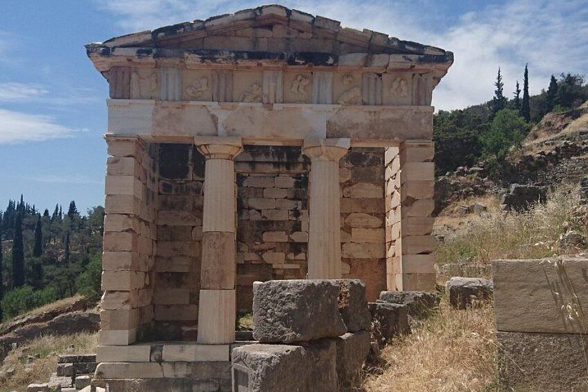 An ancient stone structure with columns, surrounded by dry grass and trees. 2