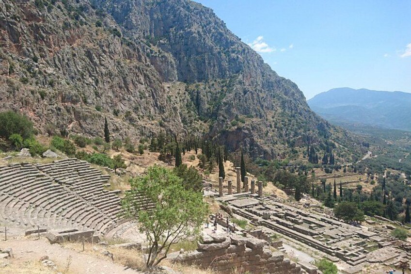 An ancient amphitheater surrounded by rocky terrain and sparse vegetation. 3
