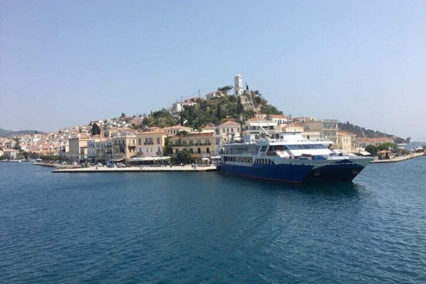 A ferry docked at a harbor with a town on a hill in the background. 3