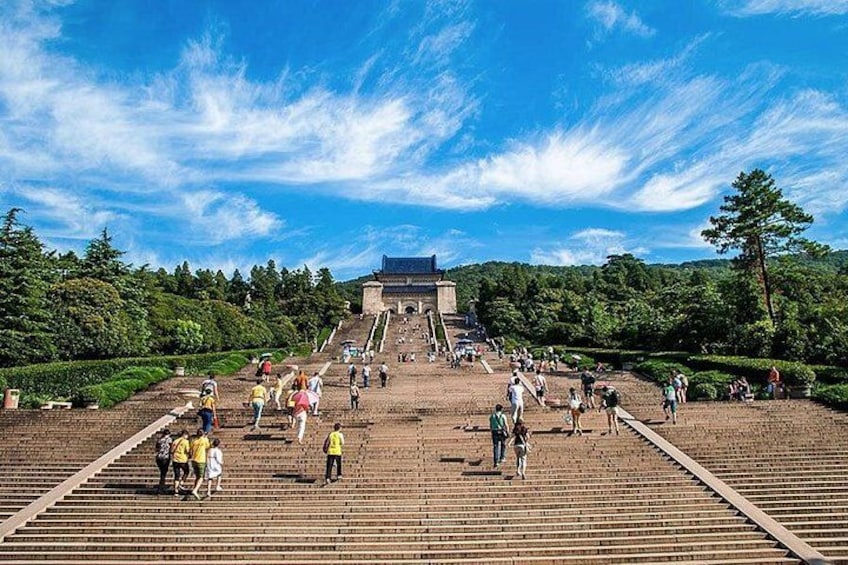A large open plaza with steps leading to a traditional building, surrounded by trees and greenery. 3