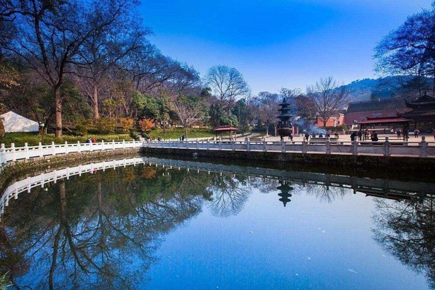 A calm lake with a white fence, trees, and traditional buildings in the background. 4