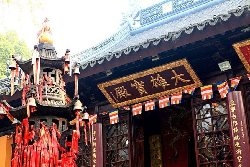 A traditional Chinese building with ornate decorations, including red flags and a bell tower. 2