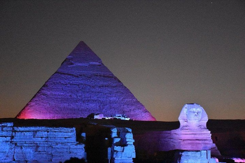 Die Große Pyramide von Gizeh bei Nacht beleuchtet, mit der Sphinx im Vordergrund. 4