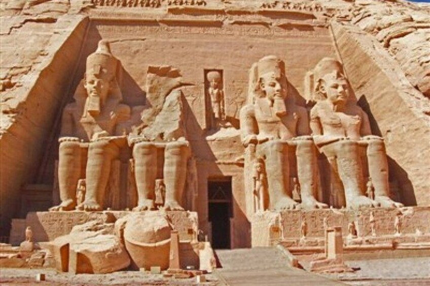 Ein großes Steingebäude mit Statuen von Pharaonen und einer Pyramide im Hintergrund. 5