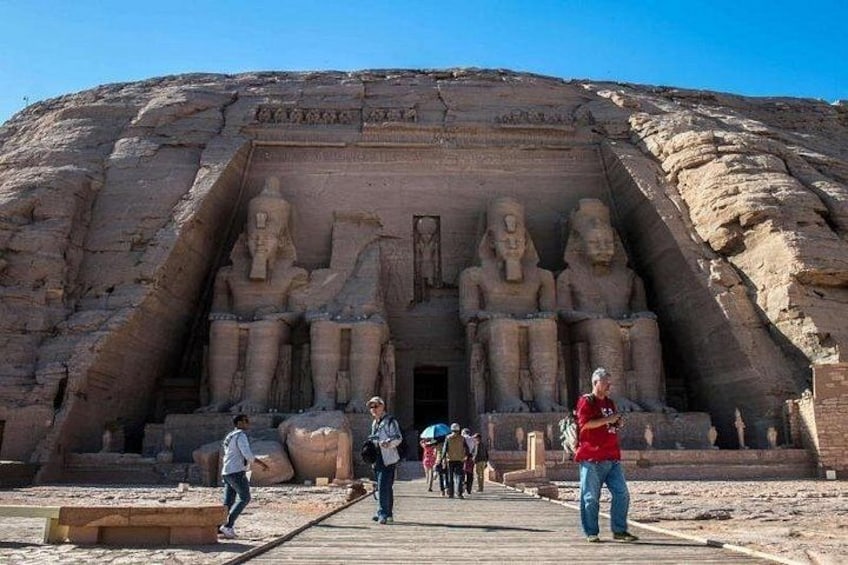 Ein großer, in Fels gehauener Tempelgang mit sitzenden Statuen und Besuchern. 4