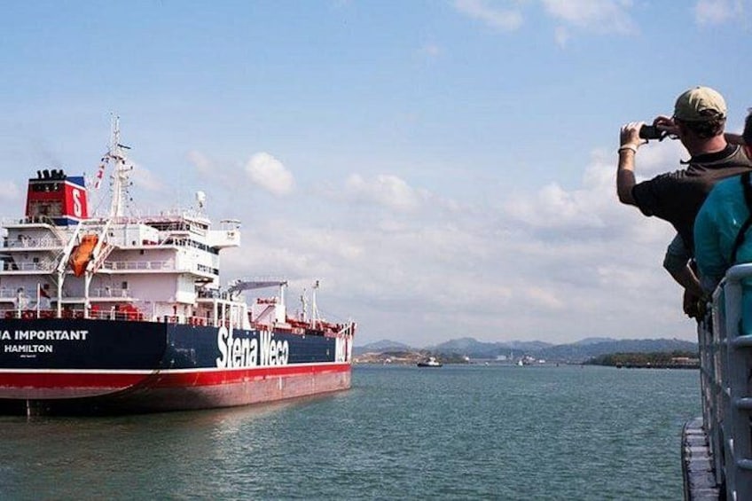 A large cargo ship named 'Sterna Wega' docked at a port with a person taking a photo. 2