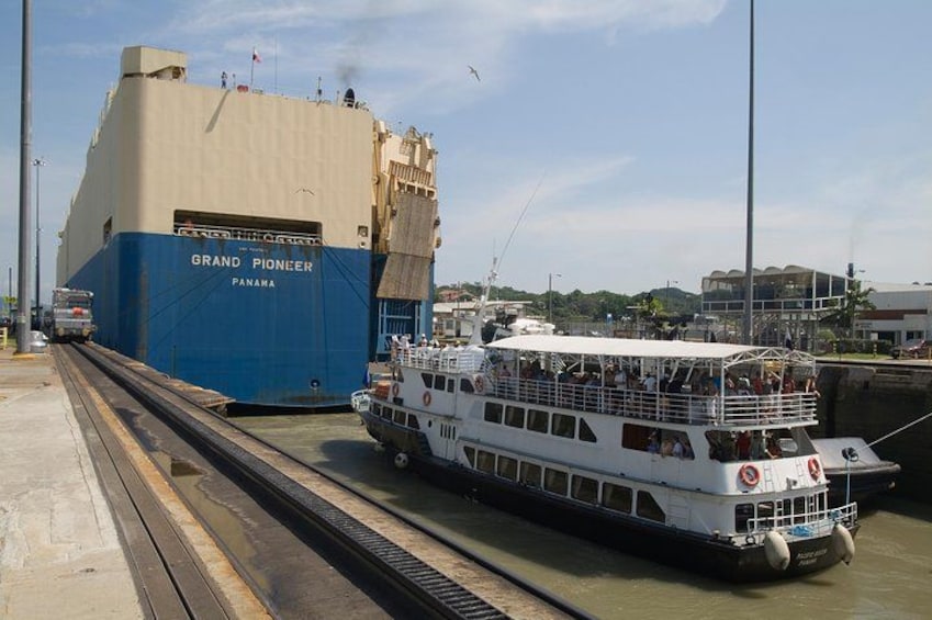 A ferry named 'Grand Pioneer Panama' docked at a port with a white boat on the water. 3